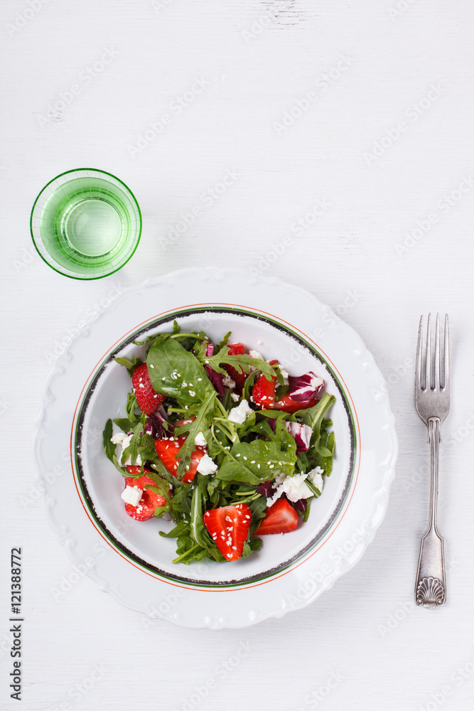 Salad of fresh strawberries,arugula,lettuce,cheese and sesame seeds .healthily cooking concept.selective focus. Salad of fresh strawberries,arugula,lettuce,cheese and sesame seeds .healthily cooking concept.selective focus.