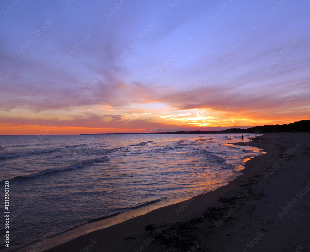 A mother and two children on the beach at sunset.