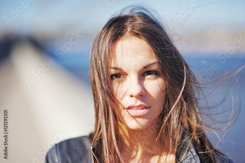 Portrait of a young cute brunette with tousled hair in the wind