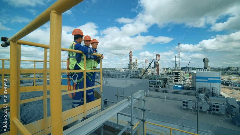 Workers in production plant as team discussing, industrial scene in background