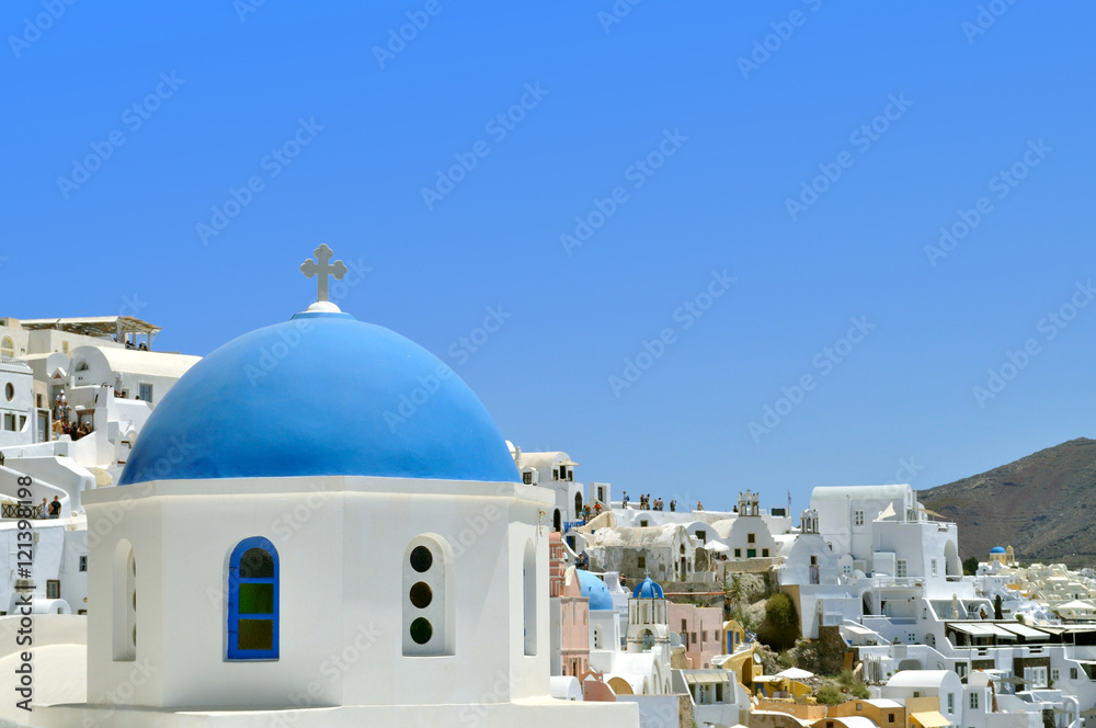 Blue domed church overlooking the Aegean Sea at Oia - Santorini Island in Greece.