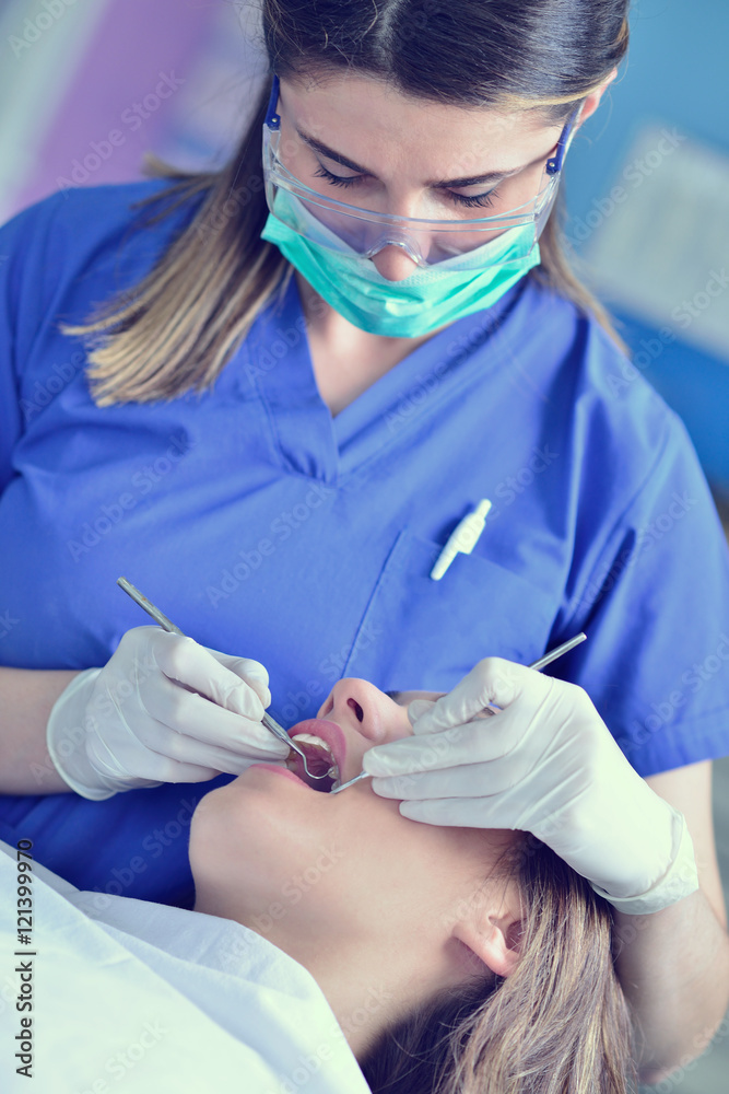 A pretty young woman with a bright, white smile lying in the dentist's chair having a checkup