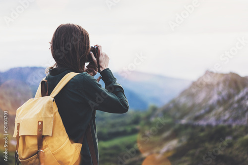 Tourist traveler photographer taking pictures landscape on vintage photo camera on background valley view mockup sun flare, hipster girl with backpack enjoying sunset on peak of foggy mountain