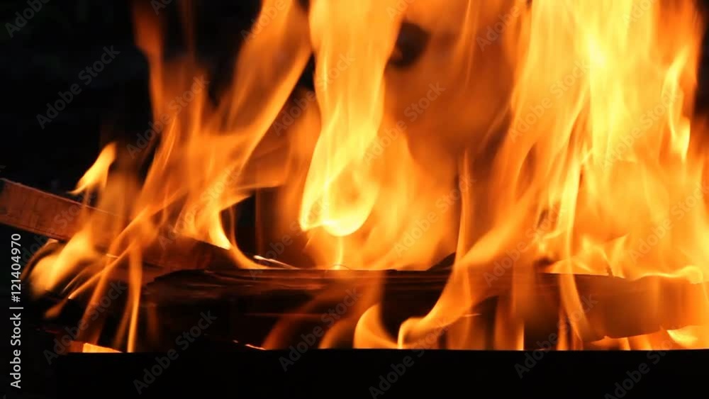 Closeup of a large fire. Wooden planks to the fire. The fire is lit in the night. Closeup of a large fire. Wooden planks to the fire. The fire is lit in the night.