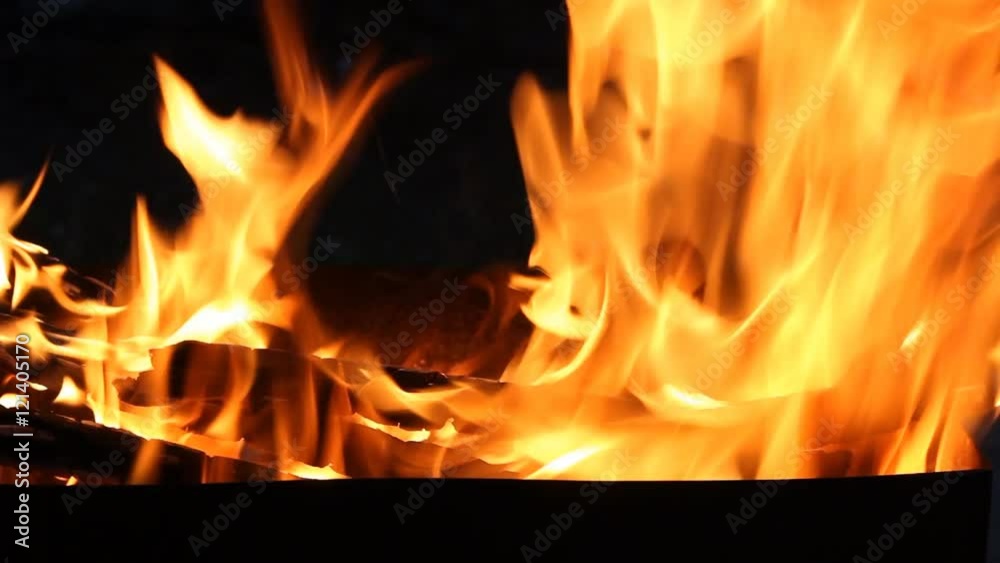 Closeup of a large fire. Wooden planks to the fire. The fire is lit in the night. Closeup of a large fire. Wooden planks to the fire. The fire is lit in the night.