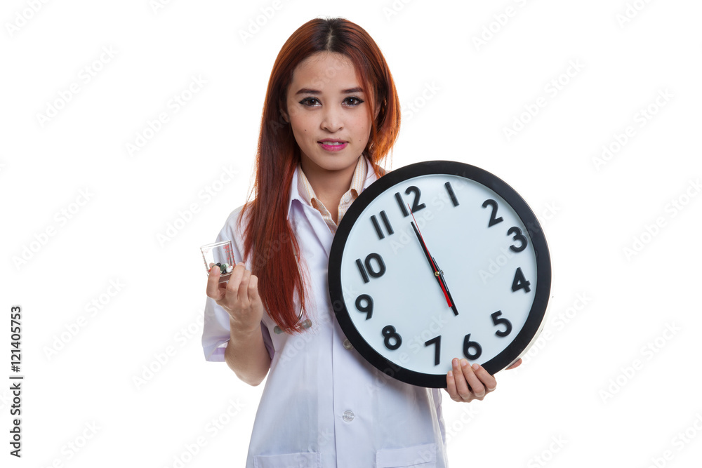 Young Asian female doctor smile with a clock and pills in hand. Young Asian female doctor smile with a clock and pills in hand.