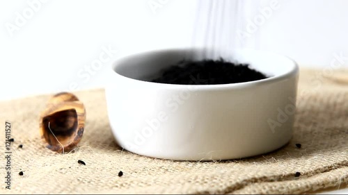 Black onion seeds pouring from above into a bowl photo