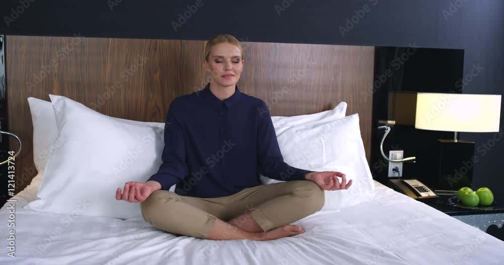 Business woman meditating in the lotus position on the bed/Business woman meditating in the lotus position on the bed. She think about successful negotiation and signing of the contract Business woman meditating in the lotus position on the bed/Business woman meditating in the lotus position on the bed. She think about successful negotiation and signing of the contract