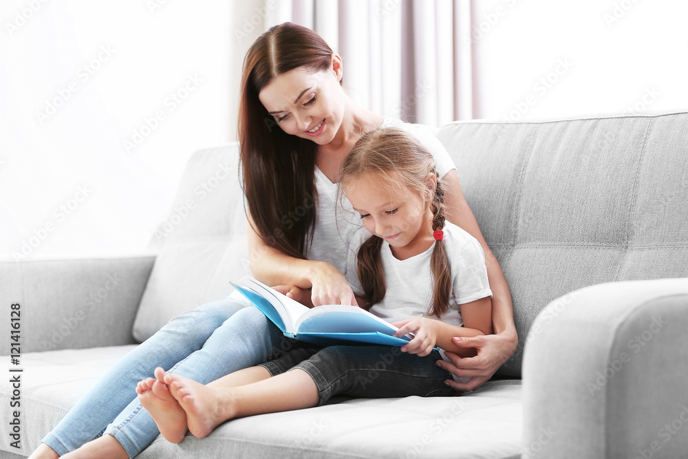 Happy mother with daughter reading book