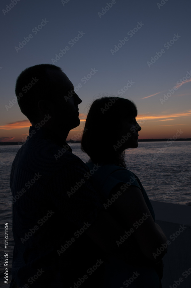 Silhouette of loving couple on sunset sky background  