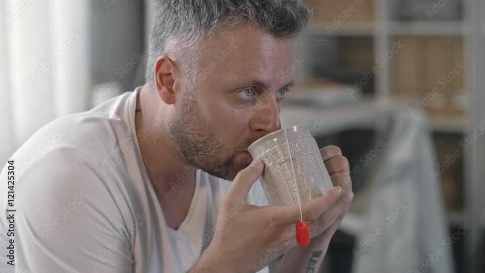 Closeup of mid-adult handsome man with stubble drinking hot tea from cup Closeup of mid-adult handsome man with stubble drinking hot tea from cup
