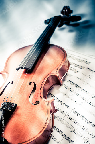 Old violin lying on the sheet of music, music concept photo