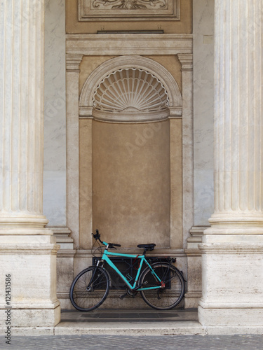 Old bicycle is standing between the columns of old building
