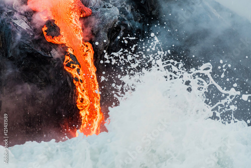 Photographer on cliff watching molten lava flowing into the Pacific Ocean from Kalapana lava flow