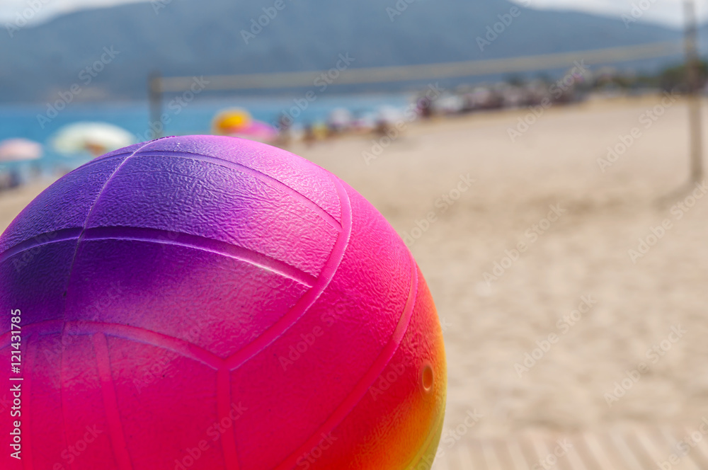 Beach volleyball ball in the foreground on the sand beach