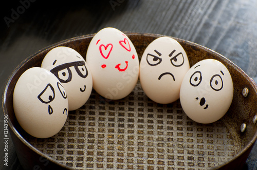 Whole eggs in a frying pan with different emotions