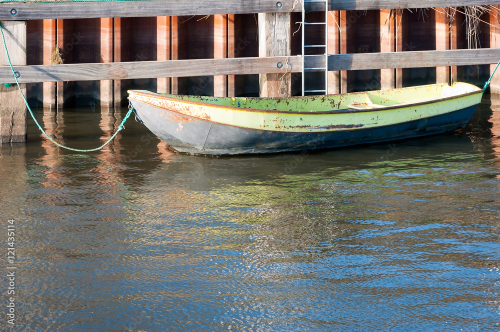 Obraz premium Old iron rowing boat moored at a wooden quayside