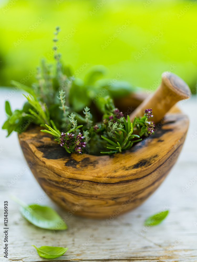 Fresh and aromatic herbs in wooden mortar.
