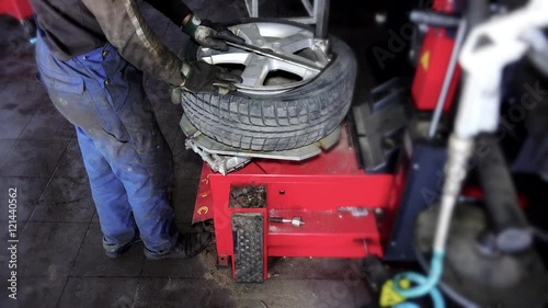 auto mechanic using special equipment to change tires in garage.