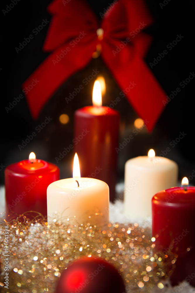 Candles and red ball with glitter in the snow, ribbon in the bac