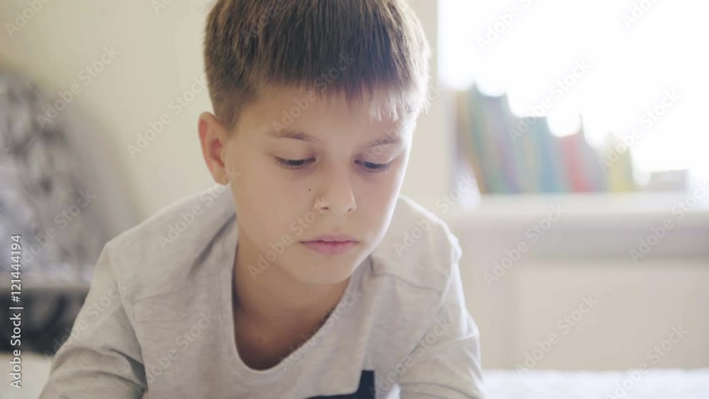 Concept of technology and lifestyle in teens life. Young teenage boy looking at digital tablet in bed. 4K video Concept of technology and lifestyle in teens life. Young teenage boy looking at digital tablet in bed. 4K video