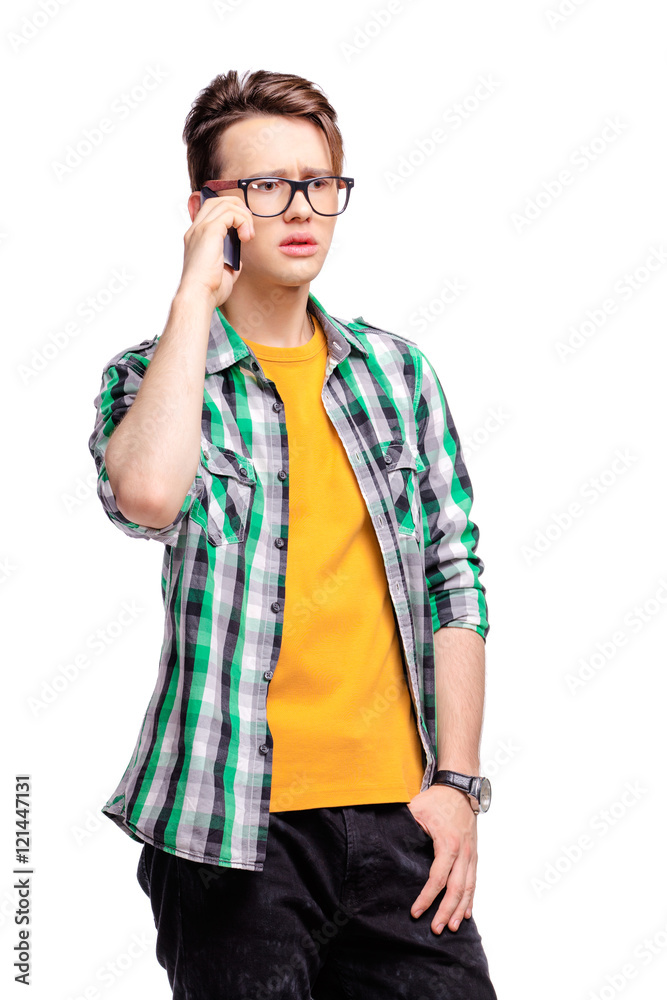 Studio portrait of confused young man talking on mobile phone. Isolated on white. Studio portrait of confused young man talking on mobile phone. Isolated on white.