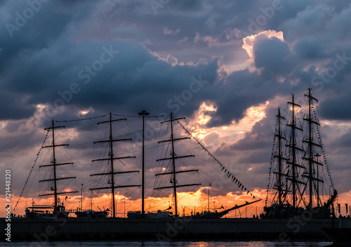 Two large sailing ships in the port at sunset background.