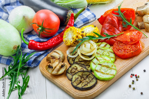 Vegetables roasted on a grill: tomato, corn, eggplant, mushroom, bell pepper, marrow and onion. Delicious healthy food and ingredients on a table. Close-up shot.