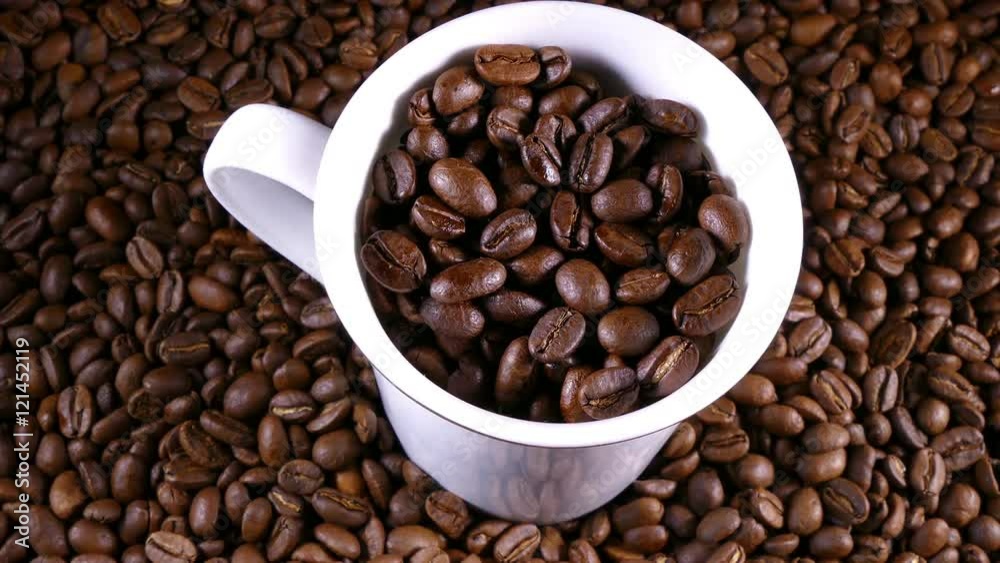 Circular dolly shot of coffee beans and a cup.
