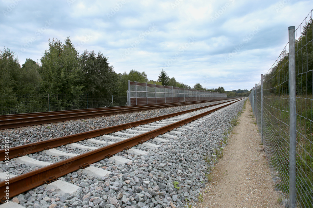Railway with noise damping wall. Rail Baltica railroad protective fences.