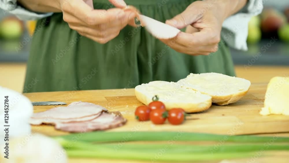 Woman cutting tomato into slices in the kitchen while preparing sandwich, dolly shot
Woman cutting tomato into slices in the kitchen while preparing sandwich, dolly shot