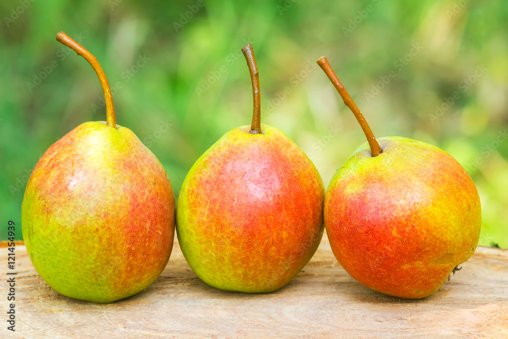 Three ripe organic pears on wooden board, blurred background, selective focus. Three ripe organic pears on wooden board, blurred background, selective focus.