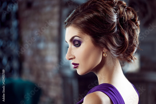 Beauty Brunette model woman in evening purple dress. Beautiful fashion luxury makeup and hairstyle.