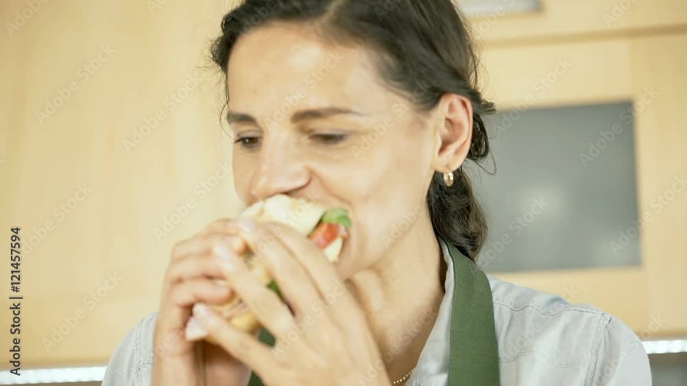 Woman eating freshly made, delicious sandwich and smiling to the camera, dolly shot
Woman eating freshly made, delicious sandwich and smiling to the camera, dolly shot