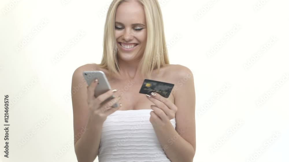 Happy attractive woman entering credit card numbers to mobile phone Happy attractive woman entering credit card numbers to mobile phone