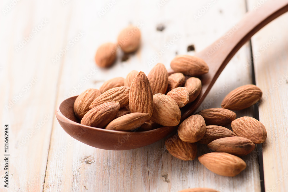 Almonds pour from wood spoon Almonds pour from wood spoon