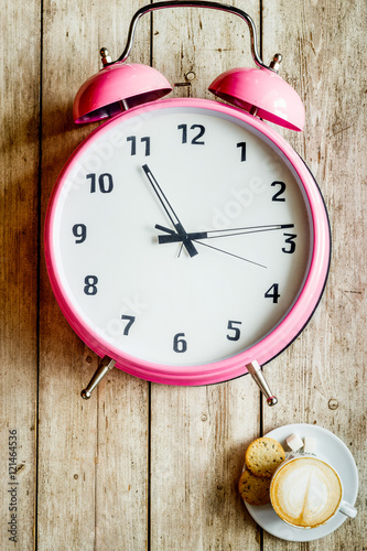 Fototapeta Naklejka Na Ścianę i Meble -  pink alarm clock on wooden table with coffie top view