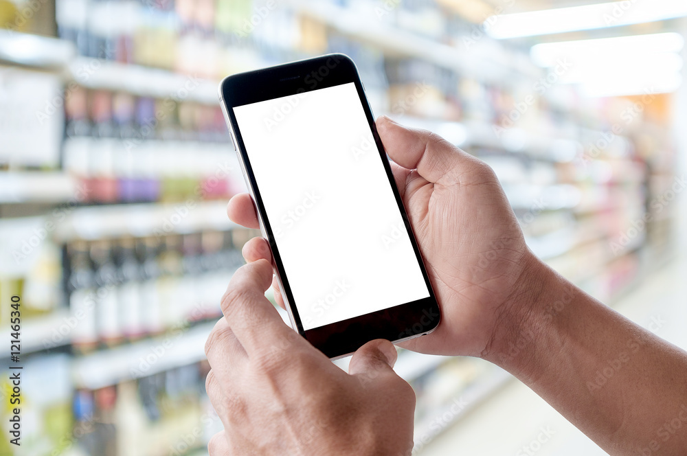 Hand holding blank screen of smartphone device in supermarket. Hand holding blank screen of smartphone device in supermarket.