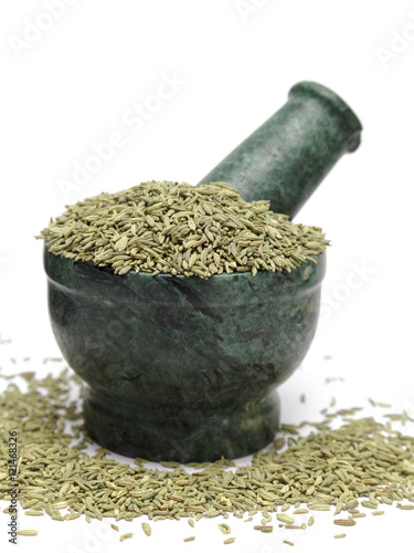 Organic Indian Fennel seed (Foeniculum vulgare) on marble pestle and over white background photo