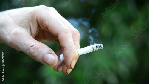 Man hand with a cigarette on background of nature