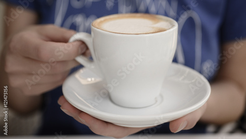 Woman holding cup of hot coffee cappuccino