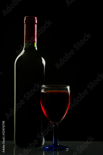 Glass and bottle of wine isolated on a black background