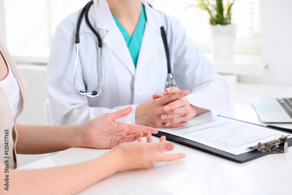Doctor and patient are discussing something, just hands at the table Doctor and patient are discussing something, just hands at the table
