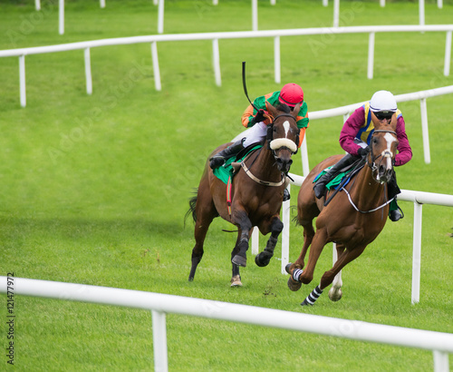 Two jockeys and race horses competing for position around the bend on the track