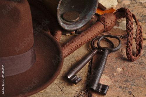 Fedora hat, bullwhip and relics on an antique tiled floor. Indiana theme photo