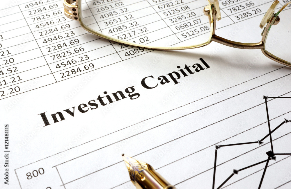 Sign investing capital on a paper and glasses. Sign investing capital on a paper and glasses.