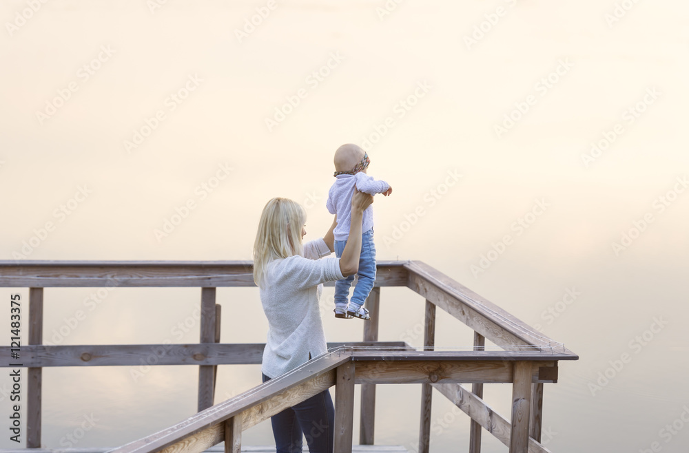 Mother and the little daughter are on the river jetty. Sunset. Fog. Mother and the little daughter are on the river jetty. Sunset. Fog.