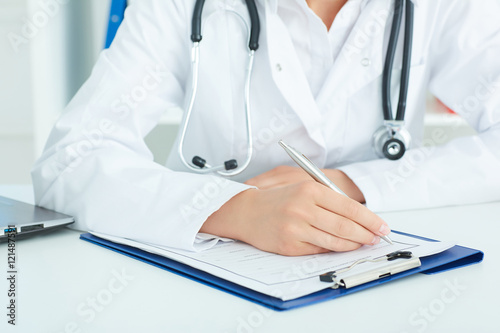 Female medicine doctors hands filling patient medical form. ealth care, insurance and help concept.