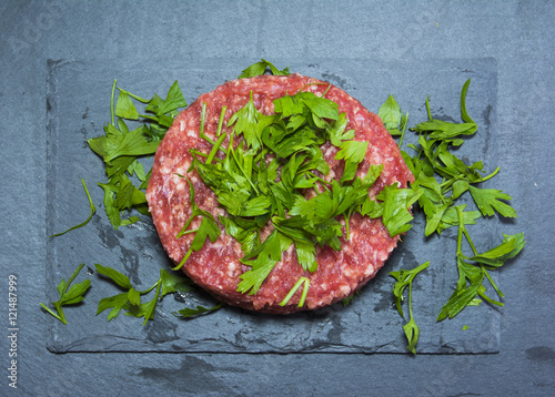 Raw hamburgers with parsley on a stone slate