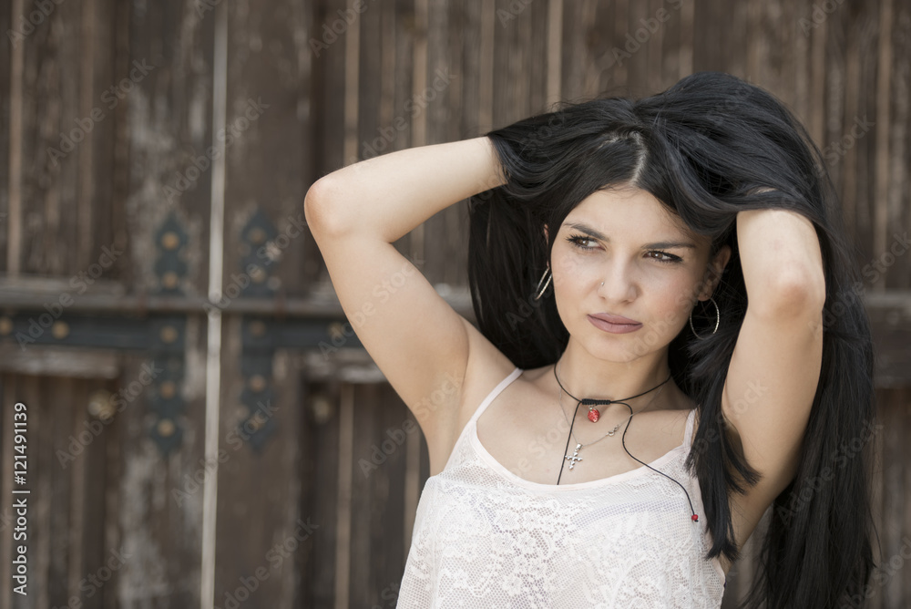Fototapeta premium Portrait of a woman with a nice beautiful face standing against old wooden door